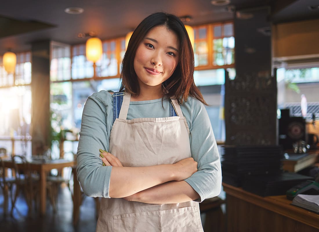 Insurance Solutions - Portrait of a Young Asian Small Business Owner Standing Inside her Restaurant with her Arms Folded