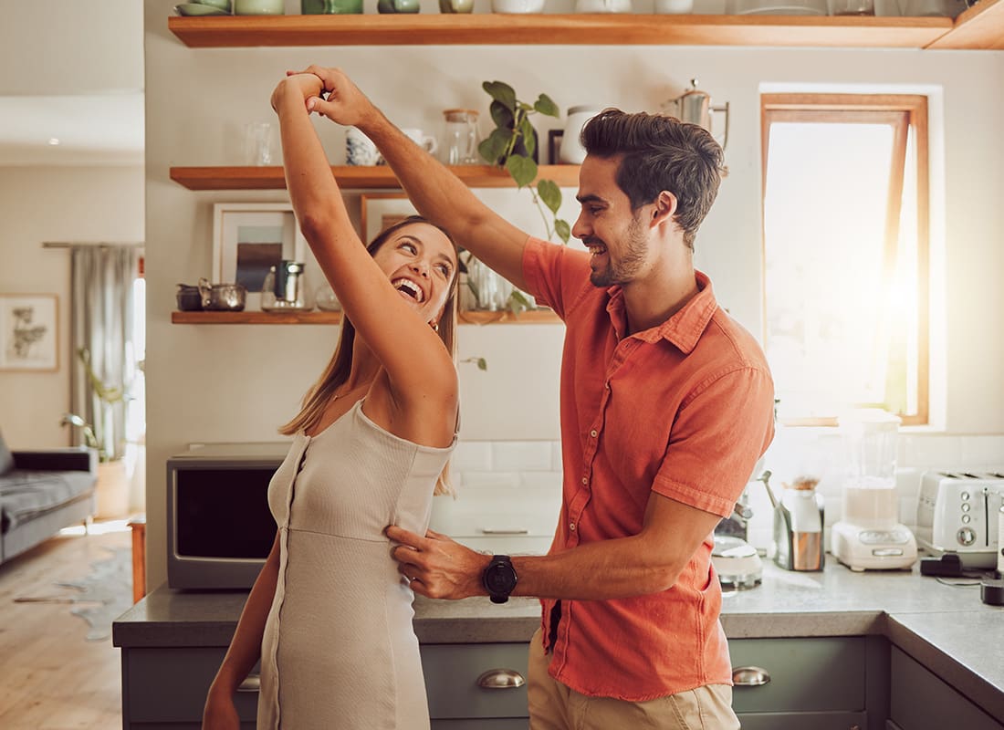 Read Our Reviews - Cheerful Young Married Couple Having Fun Dancing in the Kitchen of Their Home